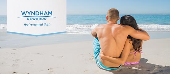 A couple sitting on the beach signifying the Wyndham rewards you can earn by stay at the Days Inn Stephenville hotel