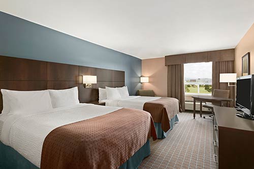 A spacious double queen bedroom at the Days Inn Stephenville hotel located near the St. George blueberry festival