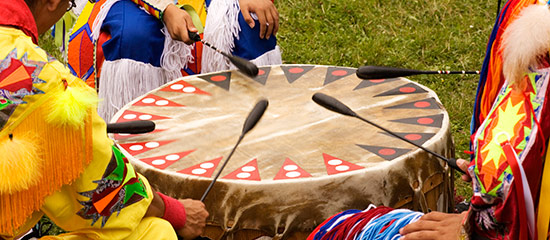 People in colorful clothing pounding on a drum at a Stephenville festival near the Days Inn Stephenville hotel